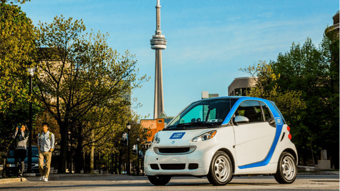 a car2go electric smart car with the CN tower in the background